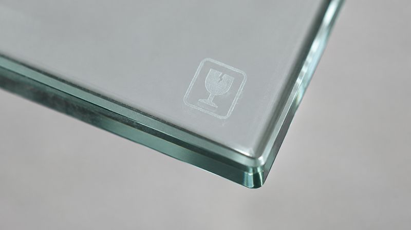 The permanent safety marking etched into the corner of a toughened glass pane